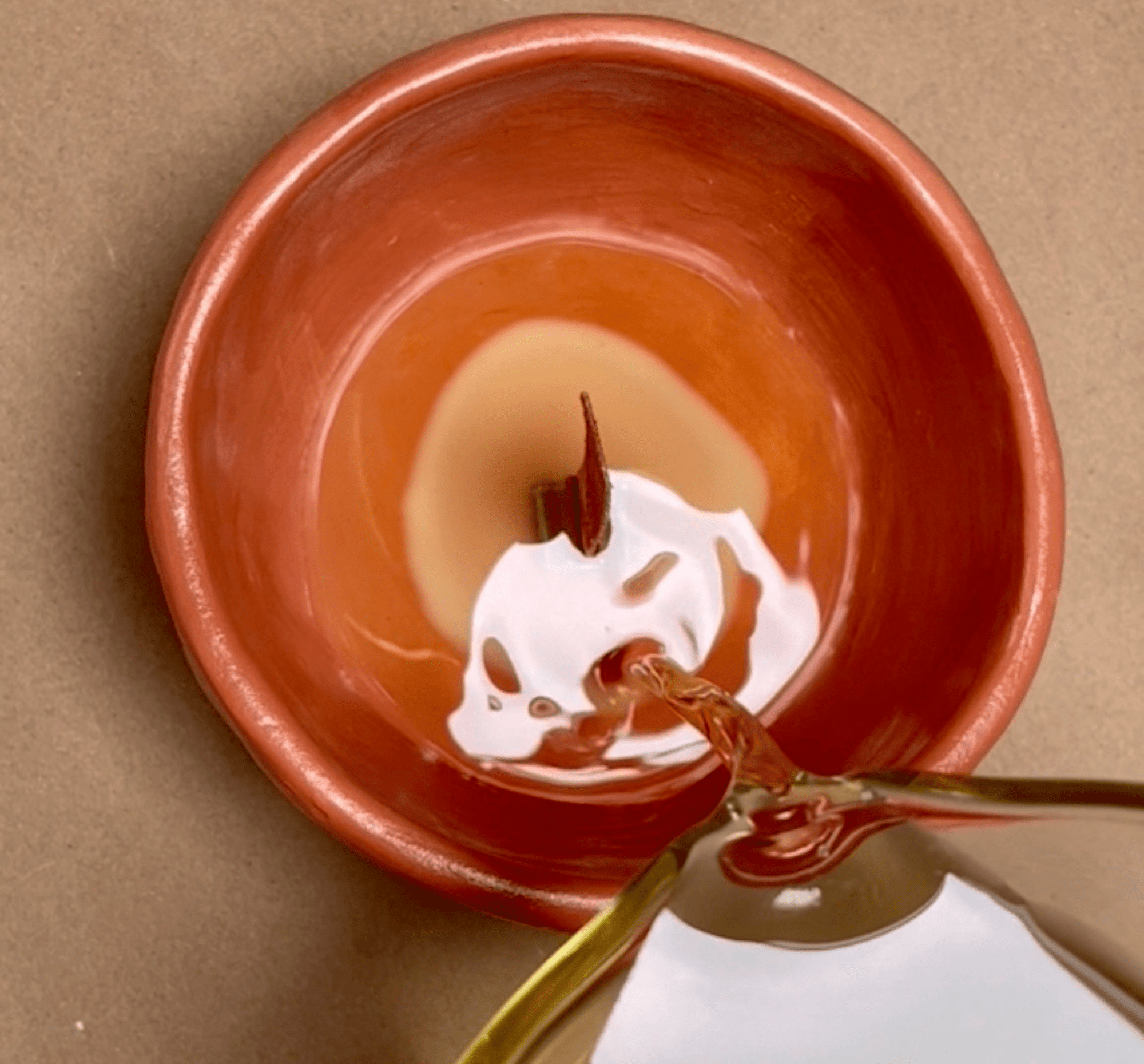 Pouring soy candle wax into an orange air dry clay vessel