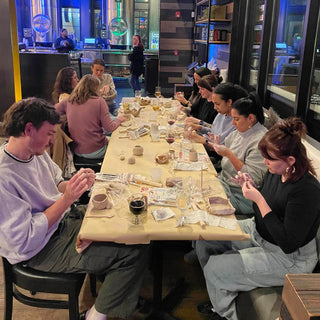 Group of people sitting around a table in a casual setting, possibly a cafe or restaurant.