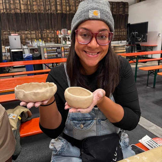 Person holding two ceramic bowls at a pottery workshop