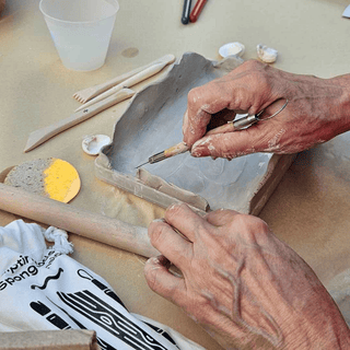 Person working on a ceramic piece with tools on a table