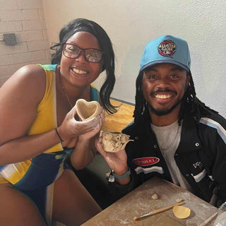 Two people holding ceramic pieces at a pottery class