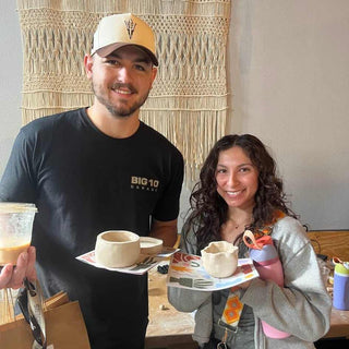 Two people holding ceramic bowls and a drink in a casual setting.