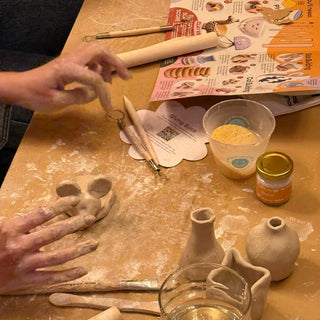 Person working with clay on a table with pottery tools and materials.