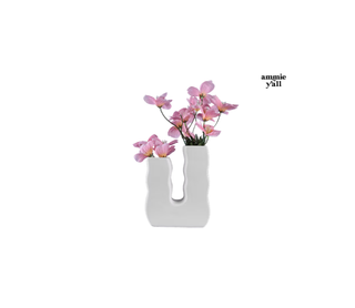 A white ceramic U-shaped vase with wavy edges, holding pink flowers, on a white background with the text 'ammie y'all' in the upper right.