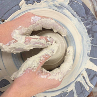 Hands working with clay on a pottery wheel