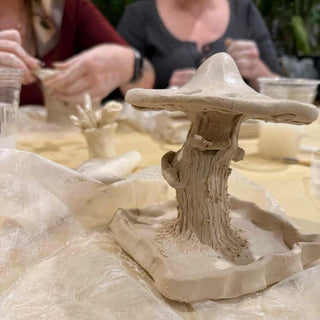 Clay mushroom cermic sculpture on a table with people working in the background