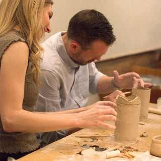 Two people working with clay at a workshop.