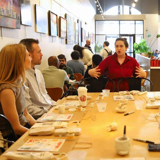 Group of people sitting around a table at a pottery class.