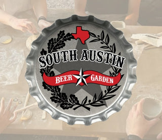 Decorative sign shaped like a bottle cap with 'South Austin Beer Garden' text and design.