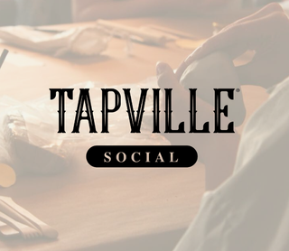 A warm-toned, softly blurred scene of a person holding a mug at a wooden table, with large overlaid text reading 'TAPVILLE SOCIAL' in the center.