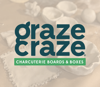A branded product graphic for Graze Craze Charcuterie Boards & Boxes, with large dark teal text over a softly blurred background of white charcuterie boards and food prep items.