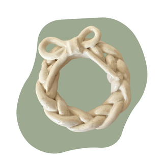 Braided beige wreath with a bow on a green background